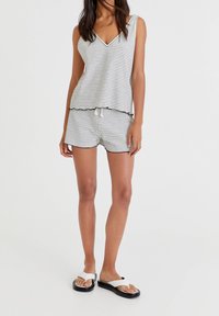 Canottiera a righe con scollatura a V, abbinata a pantaloni corti coordinati con cintura elastica. Tessuto leggero con vestibilità comoda.
