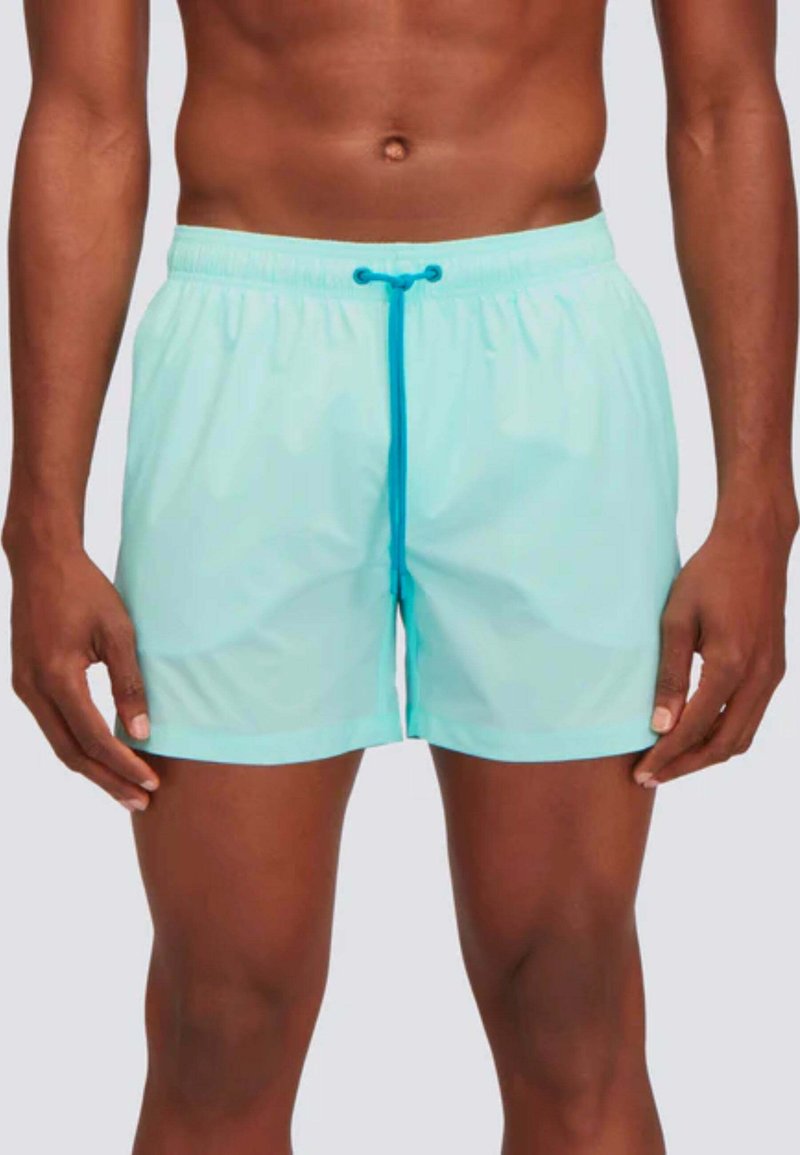 Pantaloni da mare azzurri chiari realizzati in materiale leggero, dotati di una vita elasticizzata con un laccetto blu e una superficie liscia.