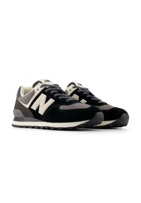 Sneaker nere e grigie con una tomaia in suede, sovrapposizioni testurizzate, una suola imbottita e un logo "N" bianco prominente sul lato.