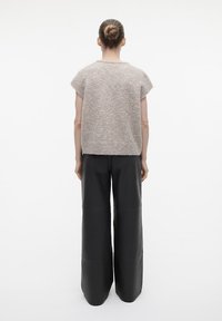 Lichtgrijs kortom mouw gebreid topje gecombineerd met wijd-uitlopende zwarte leren broek, met een losse pasvorm en minimalistisch ontwerp.