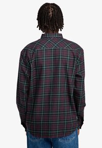 Langarm geruite blouse in donker bordeaux en groen, met een rechte snit, klassieke kraag en knoopmanchetten. Zachte stofstructuur.
