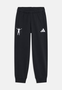 Black sweatpants feature a drawstring waist, side pockets, and white graphic designs, including a figure and the Adidas logo on one leg.