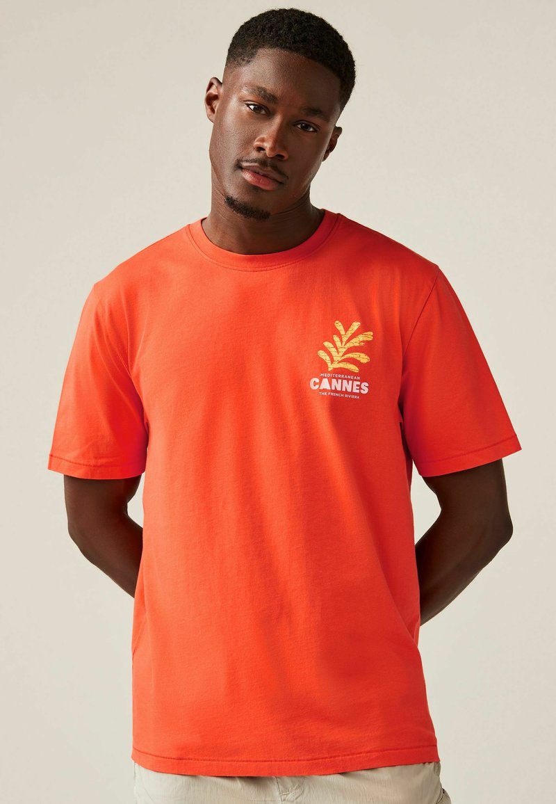 Rode katoenen T-shirt met korte mouwen. Heeft een gele palmgraphic en het woord "CANNES" op de voorkant. Ronde hals, casual pasvorm.