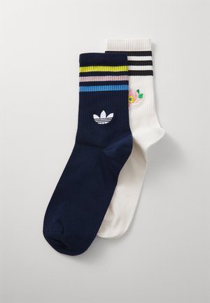Meias azul e branca em relevo, uma com riscas multicoloridas e um design floral bordado, com um logotipo branco na meia azul.