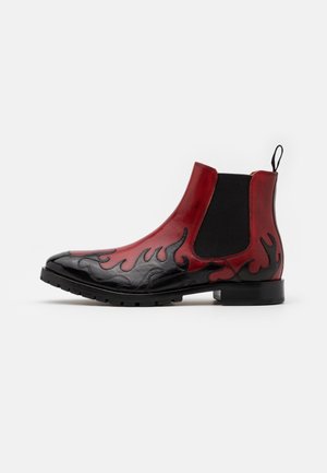 Botas Chelsea de cuero rojo y negro con patrones de llamas, textura suave, paneles laterales elásticos y un tacón bajo y resistente.
