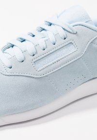 Baskets en suède bleu clair de Reebok avec des lacets assortis et une semelle blanche sur fond blanc.