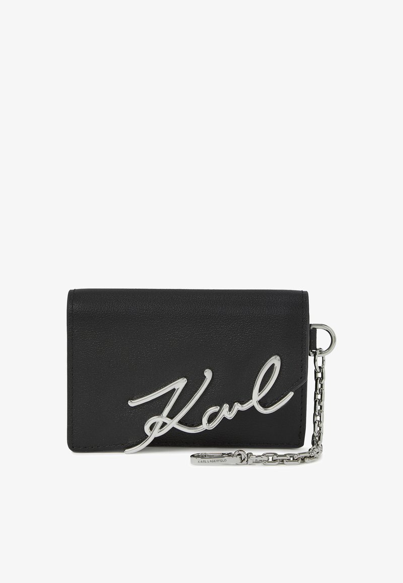 Zwarte lederen portemonnee met een zilveren metalen handtekening "Karl" logo, voorzien van een kettingaccent en een compact rechthoekig ontwerp.