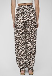 Pantalons à imprimé léopard avec une taille élastique, chevilles effilées et un tissu doux et fluide. La palette de couleurs comprend le beige, le brun et le noir.