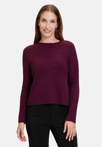 Pull en maille bordeaux avec un col rond, un ourlet côtelé et des manches longues. Sa texture douce et sa coupe décontractée créent une apparence confortable.