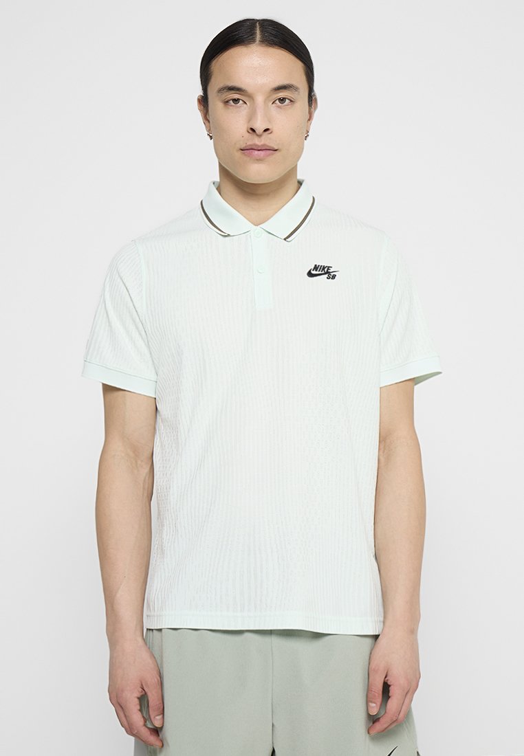 Nike SB Polo in Hellmintgrün, aus strukturiertem Material, mit kurzen Ärmeln und einem schwarzen Logo auf der Brust. Mit einem abgesetzten Kragen.
