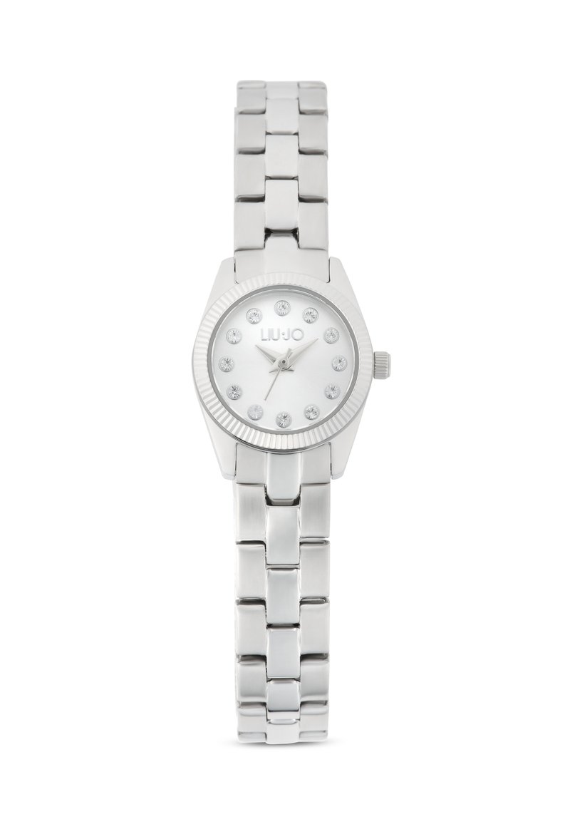 Montre argentée avec un boîtier rond, un cadran blanc comportant des index en cristal, et un bracelet en acier inoxydable.