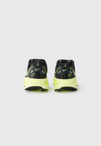 Des baskets de sport noires et jaunes fluo, dotées d'une tige en mesh respirant, d'un design de talon offrant un bon maintien et d'une semelle en caoutchouc texturée pour une meilleure adhérence.