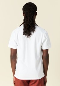 Witte katoenen t-shirt, korte mouwen, ronde hals, gladde textuur, relaxte pasvorm, weergegeven vanuit de achterkant. Geen zichtbare patronen of details.