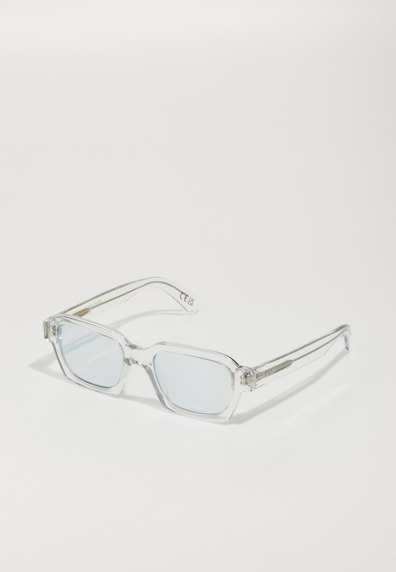 Ochelari de soare cu rame transparente și cristale pătrate, în nuanțe de albastru deschis. Prezintă accente decorative pe brațe și un design minimalist.