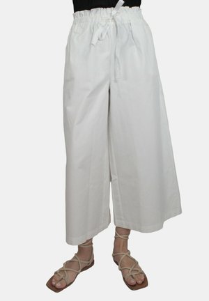 Culotte bianchi in cotone con gamba larga e un cinturino elastico dotato di cordino. Abbinati a sandali con cinturini color cuoio.