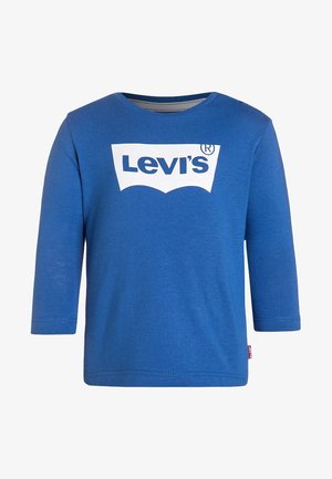 Camiseta azul de manga larga para niño pequeño con el logo blanco de Levi’s centrado en el pecho y una pequeña etiqueta roja de Levi’s en la costura lateral izquierda.