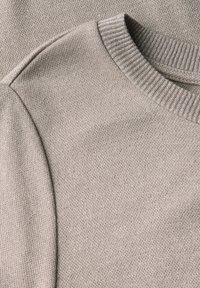 Beige pletený svetr s kulatým výstřihem a ribovanými manžetami, který se vyznačuje jemnou texturou a decentním, jednotným vzorem.