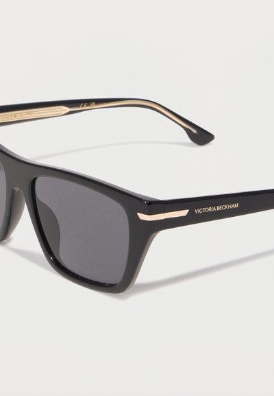 Μαύρα ορθογώνια γυαλιά ηλίου με σκούρους φακούς και χρυσές λεπτομέρειες, με το λογότυπο "Victoria Beckham" στο πλαϊνό σκελετό.