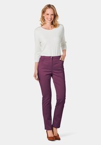 Paarse slim-fit broek met een gladde textuur en zijzakken, gecombineerd met een lang mouw witte top en bruine suède hakken.