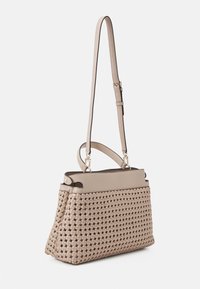 Beige vævet håndtaske med en struktureret design, der har en glat top og en justerbar rem. Bemærkelsesværdige hardware-accenter i guldtoner er til stede.