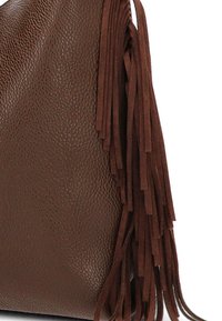 Bolso de piel marrón con una superficie texturada, que presenta largos flecos de ante en un lado. La forma general es suave y caída.
