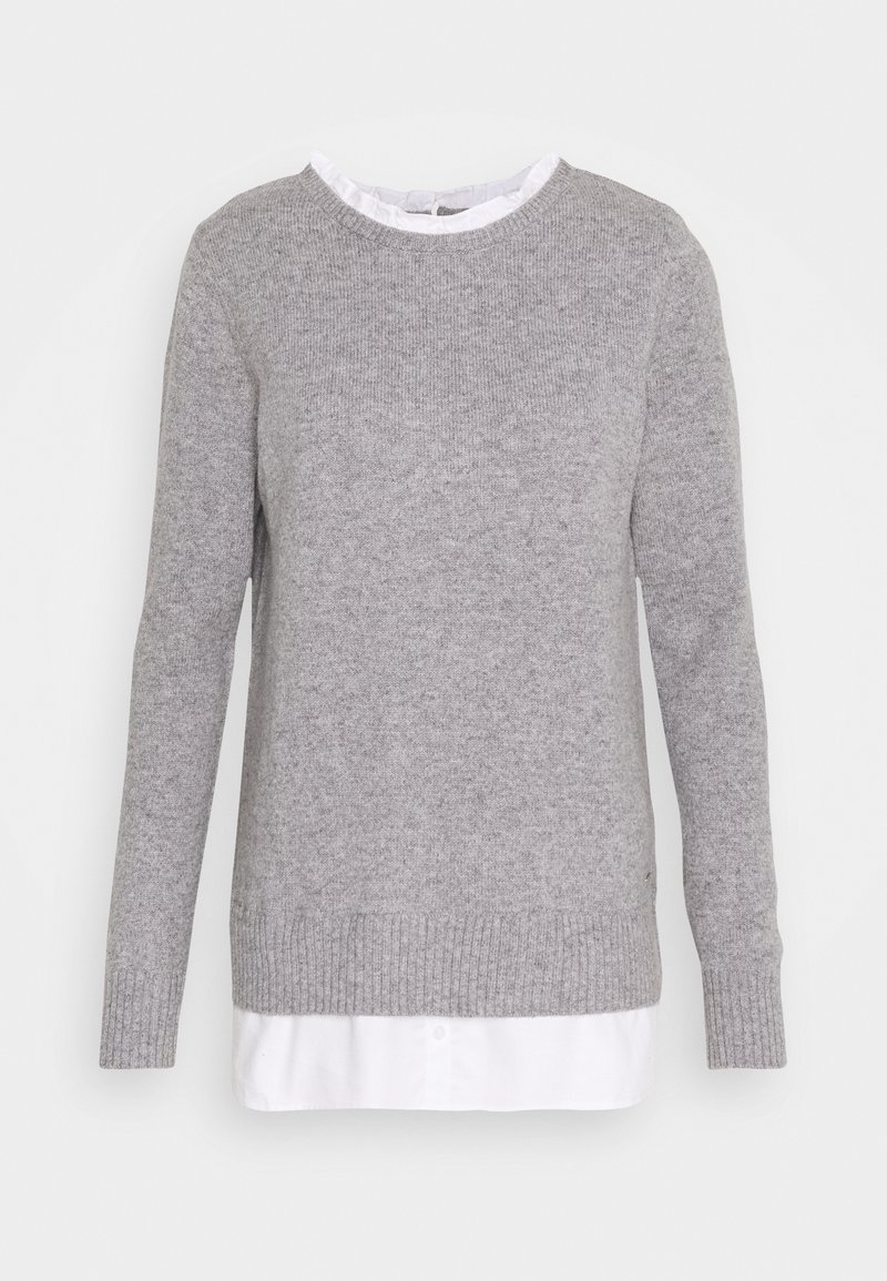 Pull en maille gris clair avec poignets et ourlet côtelés, superposé à une chemise blanche à col avec un col volanté.