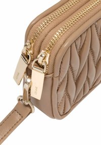 Beżowa torba skórzana pikowana z podwójnymi złotymi suwakami i akcentami. Kompaktowy design z teksturowaną powierzchnią i paskiem na ramię.