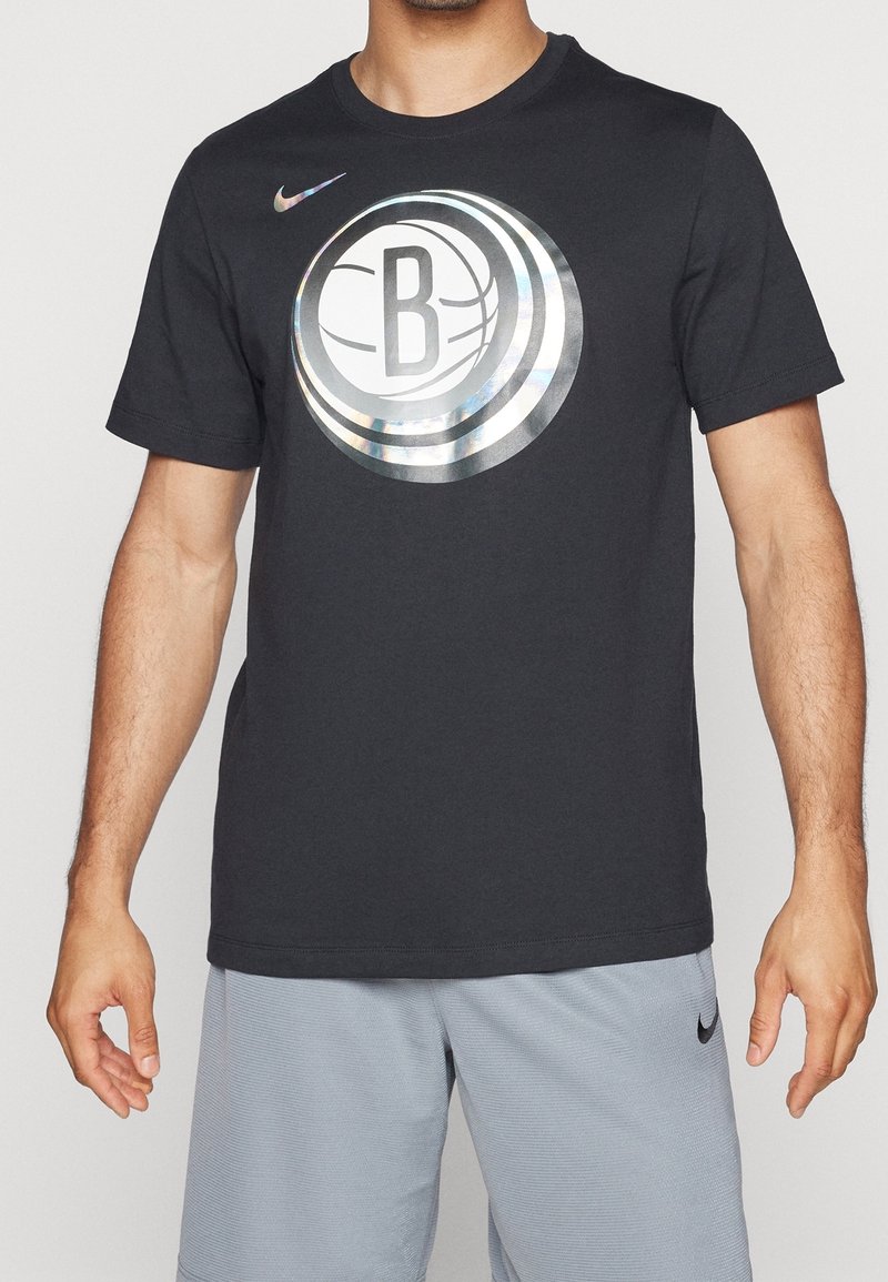 T-shirt en coton noir avec un grand logo circulaire réfléchissant de basket-ball, portant un "B" au centre. Manches courtes et col rond.