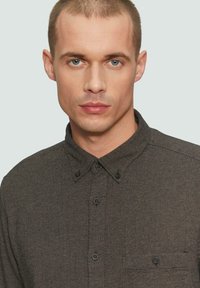 Dunkelgraues Hemd mit Knöpfen, strukturiertem Muster, spitzem Kragen und Brusttasche. Verfügt über schwarze Knöpfe an der Knopfleiste und den Manschetten.