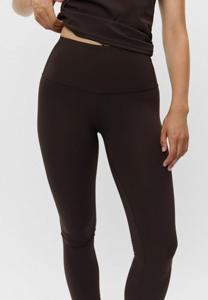 Brune højtaljede leggings lavet af strækbart materiale med en glat tekstur og flade syninger. Har et minimalistisk design og ingen synlige logoer.