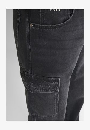 Zwarte denim cargo broek met een gestructureerde patchzak met een subtiele patroon en contrasterende stiksels. Inclusief metalen hardware.