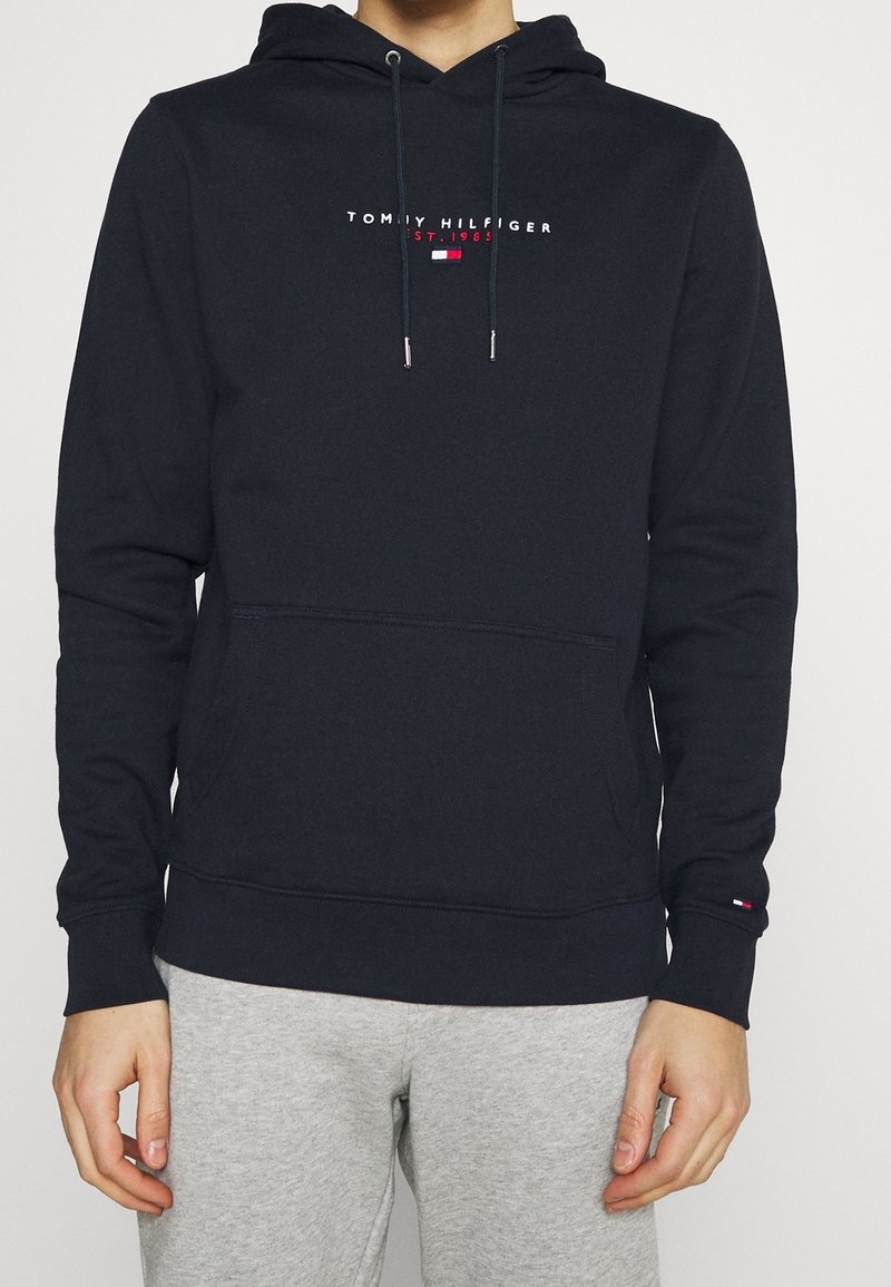 Sudadera azul marino de algodón con un bolsillo frontal, cordones y logo bordado de "Tommy Hilfiger". Puños ajustados con detalles del logo.