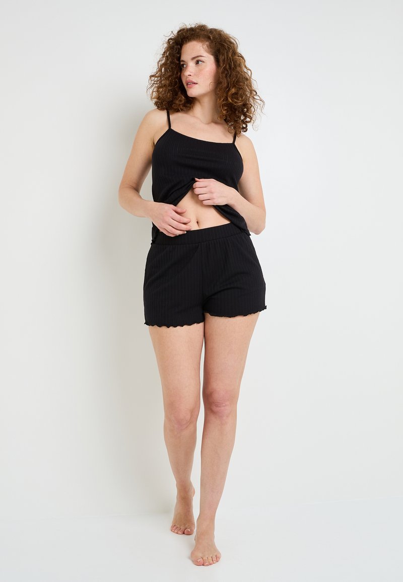 Camisole noir à côtes avec des bretelles ajustables et un short assorti. Le short a un ourlet festonné. Le matériau semble doux et léger.