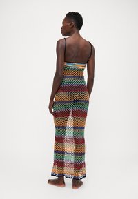 Abito maxi all'uncinetto multicolore con spalline sottili, che presenta un motivo a rete e una vestibilità ampia. Caratterizzato da strisce rosse, verdi, blu e arancioni.