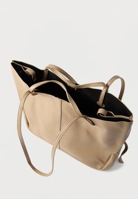 Μπεζ τσάντα ώμου από δέρμα με δύο υφασμένους χερούλια, ανοιχτό επάνω μέρος και μαύρη εσωτερική επένδυση. Διαθέτει λείο εξωτερικό και ευρύχωρο σχεδιασμό.