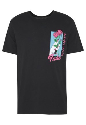 T-shirt en coton noir présentant un design graphique d'une main tenant des roses roses, avec le texte "Fake Romance" en rose sur le côté.