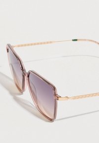 Rožinės spalvos gradientinės akiniai nuo saulės su didelia keturkampio formos rėmeliu. Aukso spalvos akcentai ant šoninių dalių su geometriniu raštu. Permatoma plastikinė medžiaga.