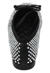 Zapato negro con una parte superior cubierta de brillantes de plata, con un diseño interior acolchado y un acento de lazo tradicional en la parte delantera.