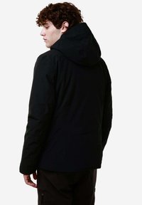 Giacca nera con cappuccio, dal finish opaco e levigato, con dettagli nelle cuciture. Presenta una silhouette aderente e tasche laterali con zip.