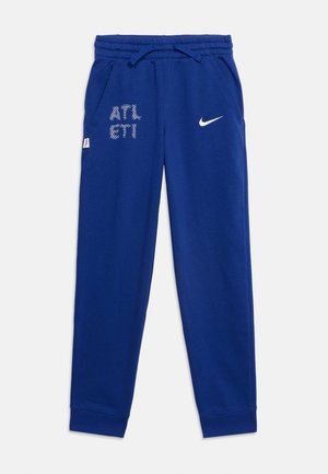 Niebieskie spodnie dresowe Nike z elastyczną talią, sznurkiem, kieszeniami bocznymi, białym logo na prawej udzie i abstrakcyjnym białym wzorem na lewym udzie.
