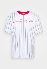 Bílý tričko s krátkým rukávem, modré vertikální pruhy, červený žebrovaný límec a červený kurzivní text "Kani Originals" na přední straně.