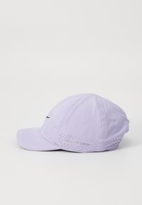 Lyselilla cap med rund krone og buet brem; har små perforeringer og en svart logo foran, med "DRI-FIT ADV" på siden.