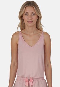 Lichtroze tanktop met dunne bandjes en een V-hals, vergezeld van bijpassende shorts met een strikkoord dat in een strik is gebonden.