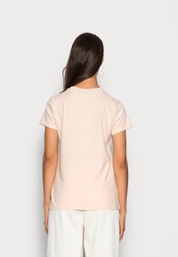 Koszulka z krótkim rękawem w jasnoróżowym kolorze, wykonana z bawełny. Prosty fason z okrągłym dekoltem, bez widocznych grafik ani wzorów.