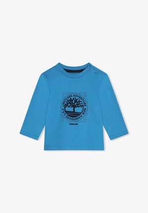 Blauwe lange mouwen t-shirt van katoen, met een zwarte boomafbeelding en tekst. Ronde halslijn met drukknopen op één schouder.