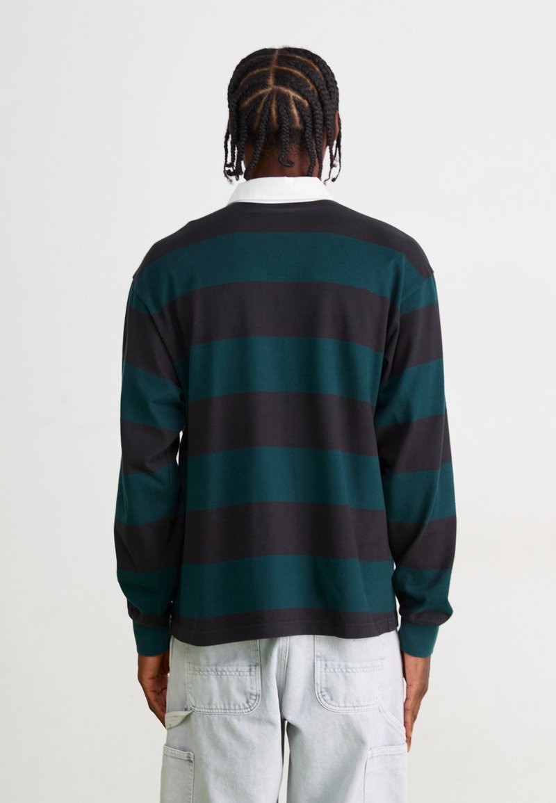 Chemise à manches longues avec des rayures horizontales noires et bleu-vert, un col blanc, fabriquée en tissu doux, avec une coupe décontractée.