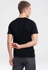 Black cotton t-shirt with short sleeves, crew neck, fitted style. Shown from the back with slight texture and seamless design.