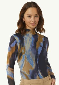 Langärmliges Rollkragenoberteil in einem fließenden abstrakten Muster aus Blau, Braun und Schwarz. Hergestellt aus glattem Stoff und mit einer taillierten Silhouette.