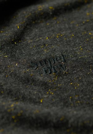 Donkergrijze stof met een gestructureerd oppervlak, voorzien van verspreide gele stippen en een zwart geborduurd logo met de tekst "Simply."