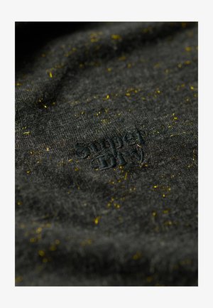 Tejido gris oscuro con una superficie texturizada, con manchas amarillas dispersas y un logo bordado en negro que dice "Simply."